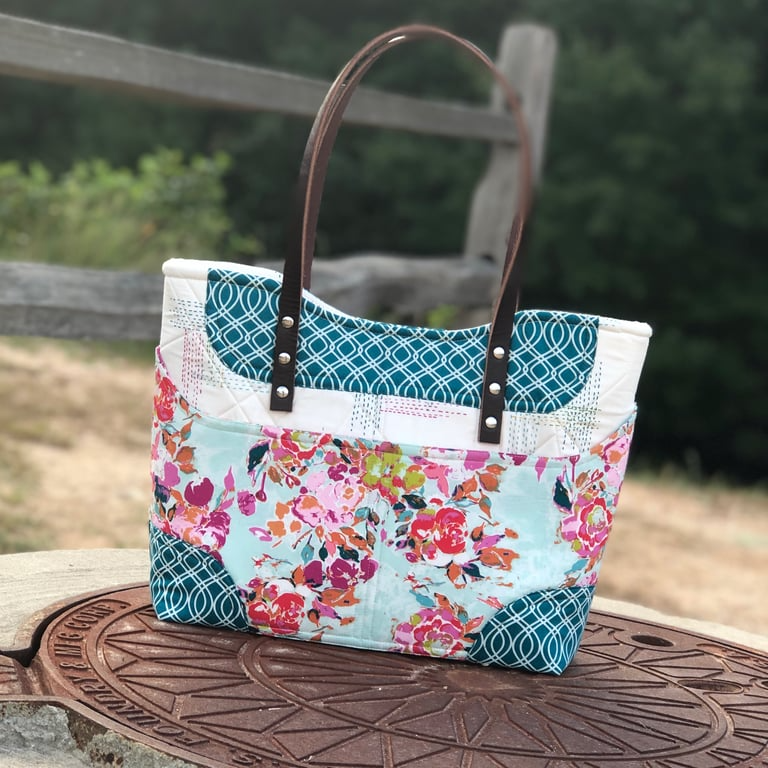 Multicolored patterned handbag on a wooden surface with a blurred natural background