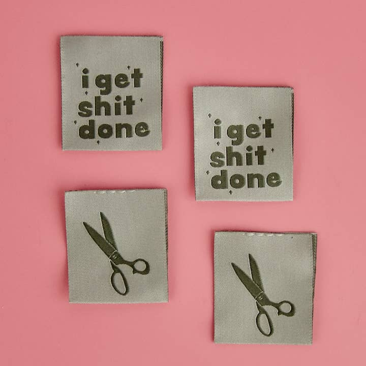 Four metallic coasters with text and scissors on a pink background