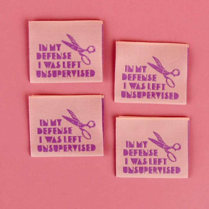 Four pink coasters with purple text and scissors on a pink background