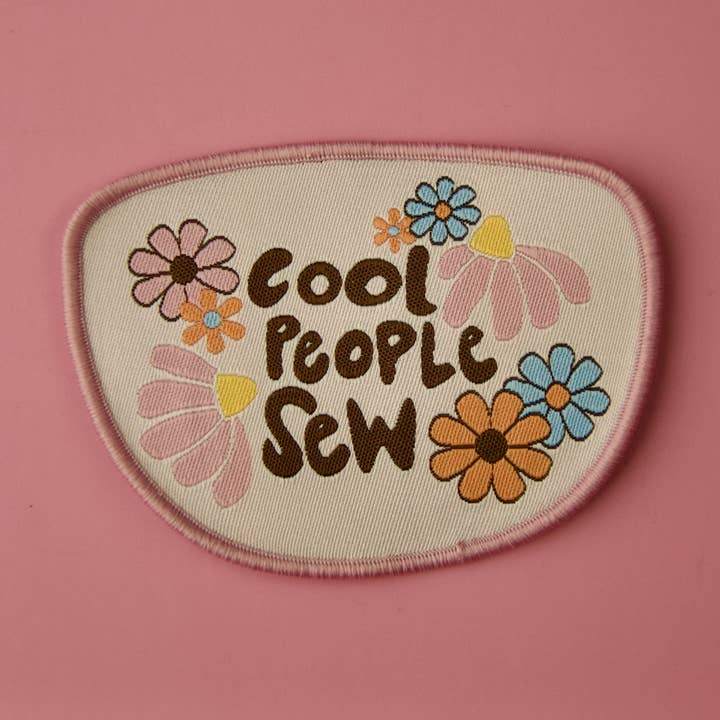 Embroidered patch with 'Cool People Sew' text and floral designs on a pink background