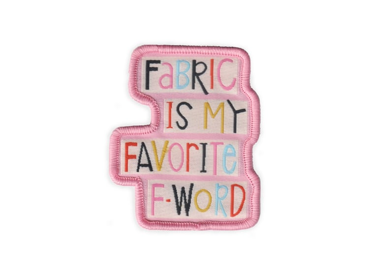 Embroidered patch with colorful text 'Fabric is my favorite F-word' on a pink border.
