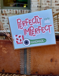 Card with 'Perfectly Imperfect' text and handmade design on a wooden surface.