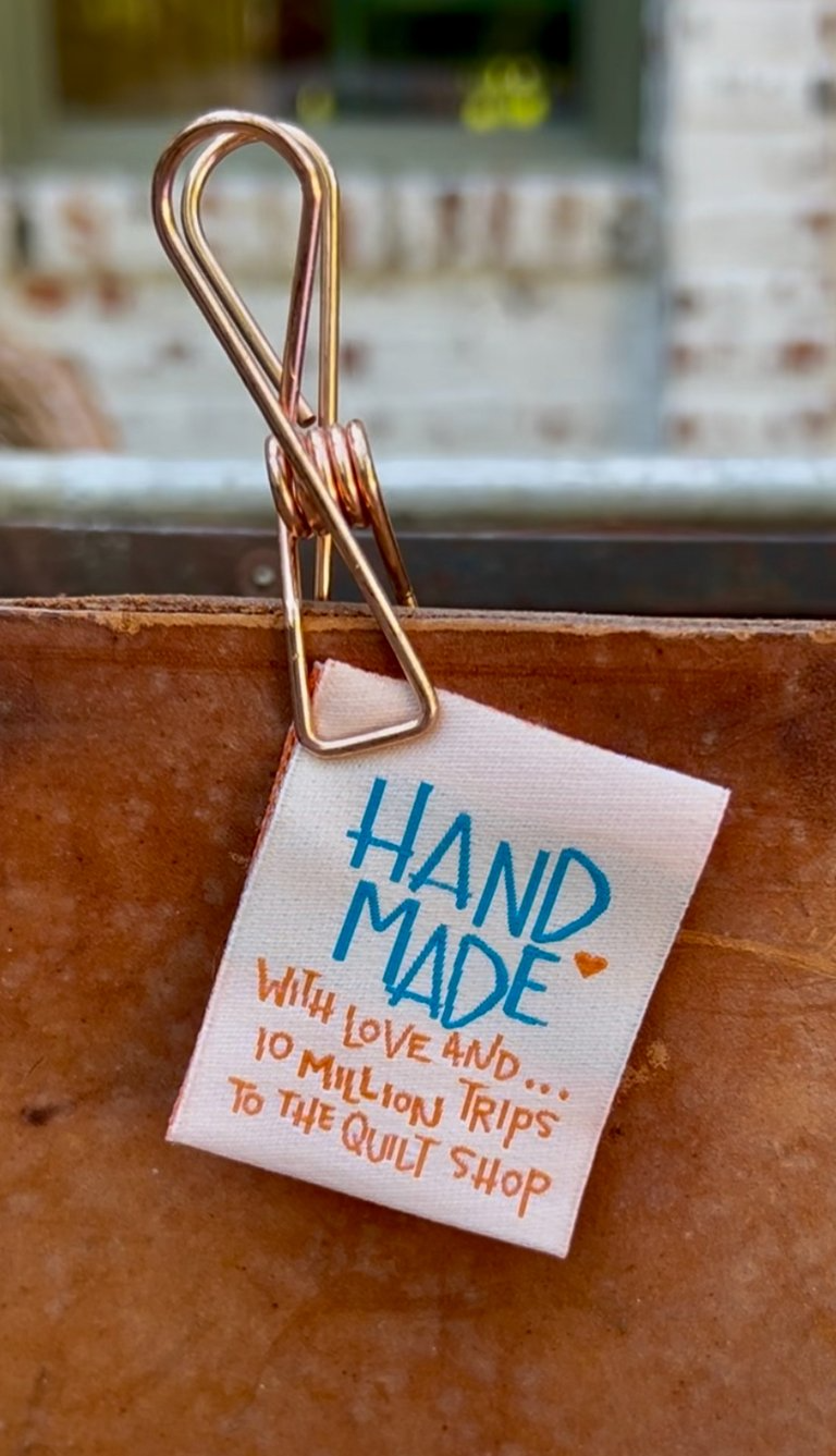 Clothing tag on a brown leather bag with 'Hand Made' text