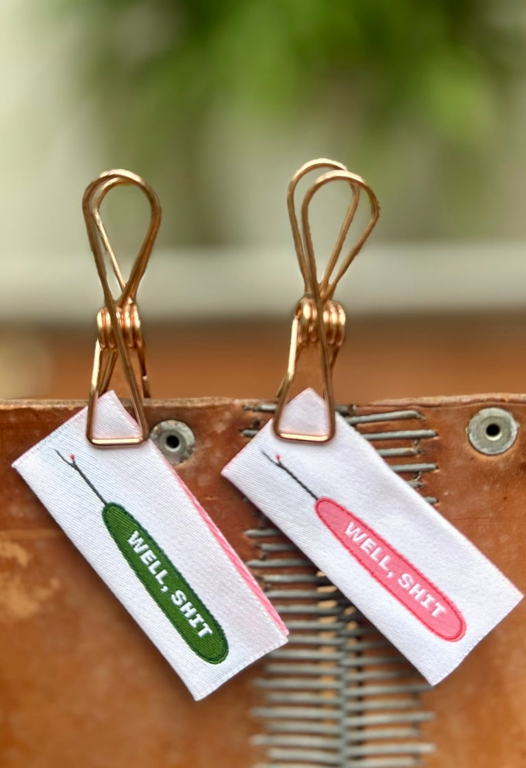 Two small tags with text attached to a leather surface.