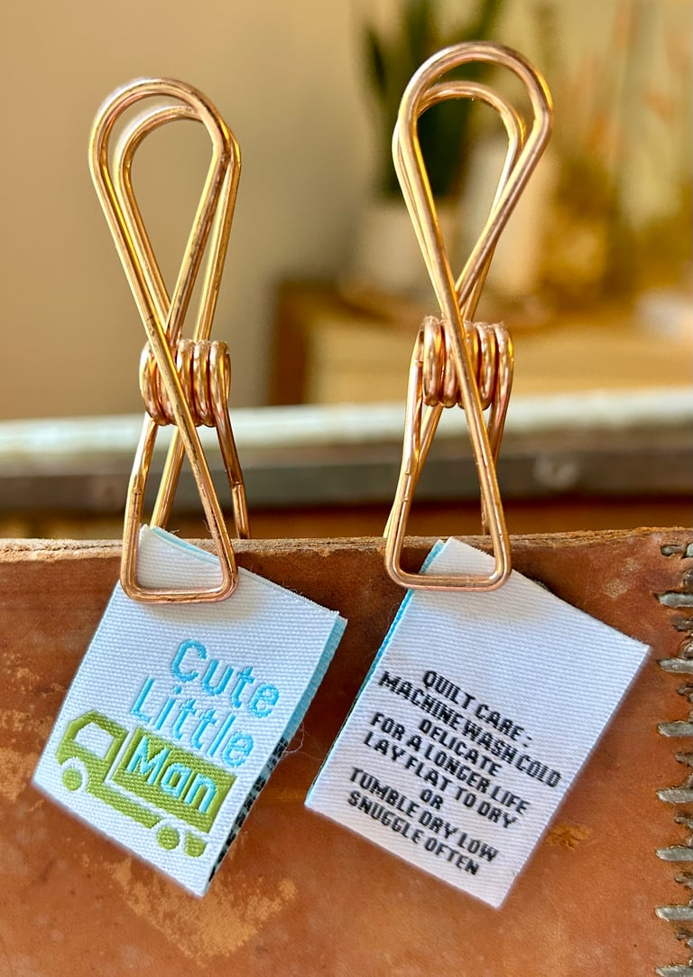 Gold paper clips with labels on a cardboard surface