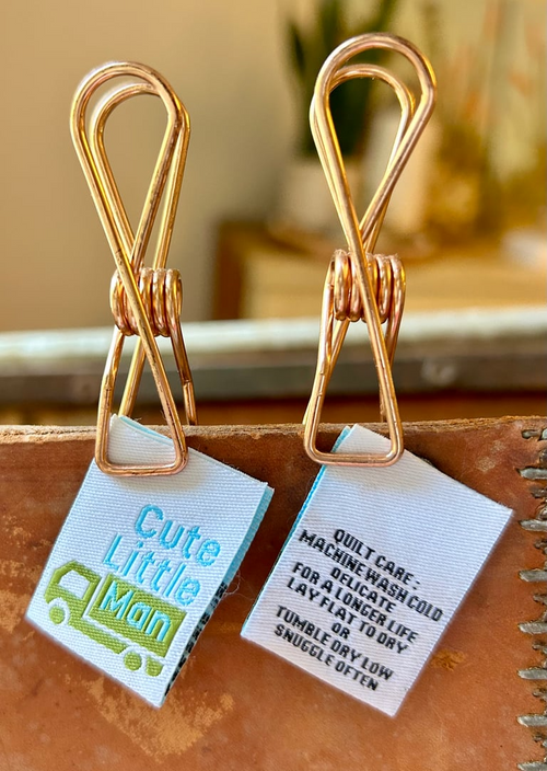 Gold paper clips with labels on a cardboard surface