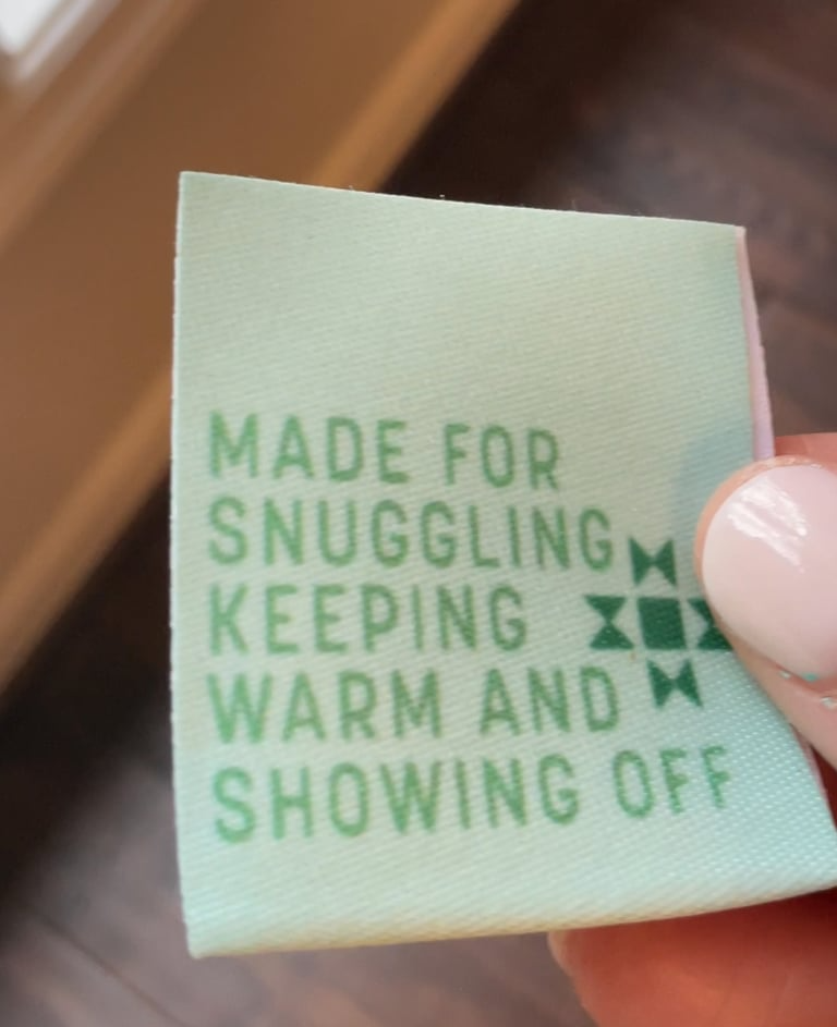 Green fabric label with text held by a hand against a blurred background