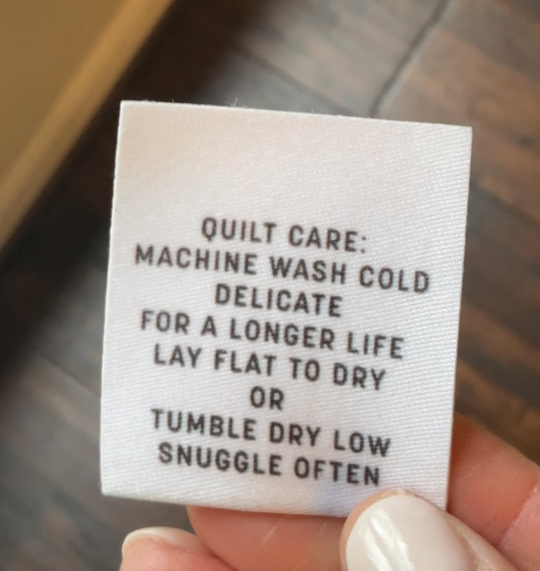 Wool label with quilt care instructions held by a hand on a blurred background