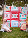 Child sitting in front of a colorful quilt outdoors