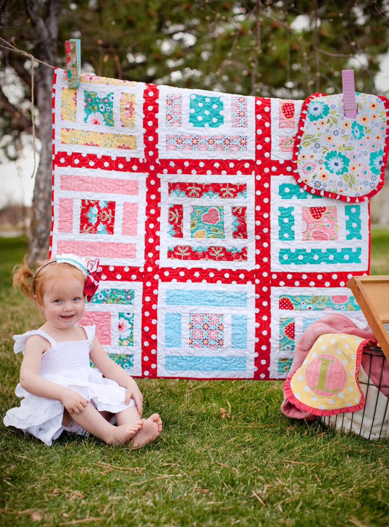 Child sitting in front of a colorful quilt outdoors