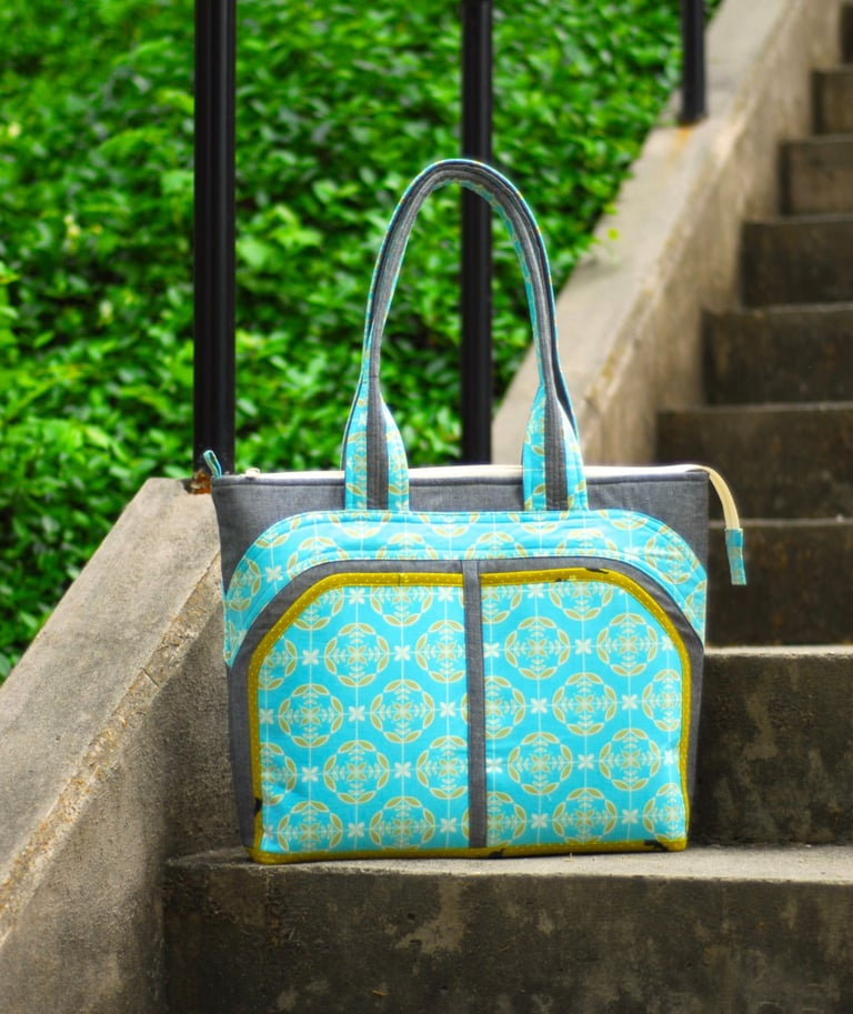 Blue patterned handbag on a stone staircase with greenery in the background