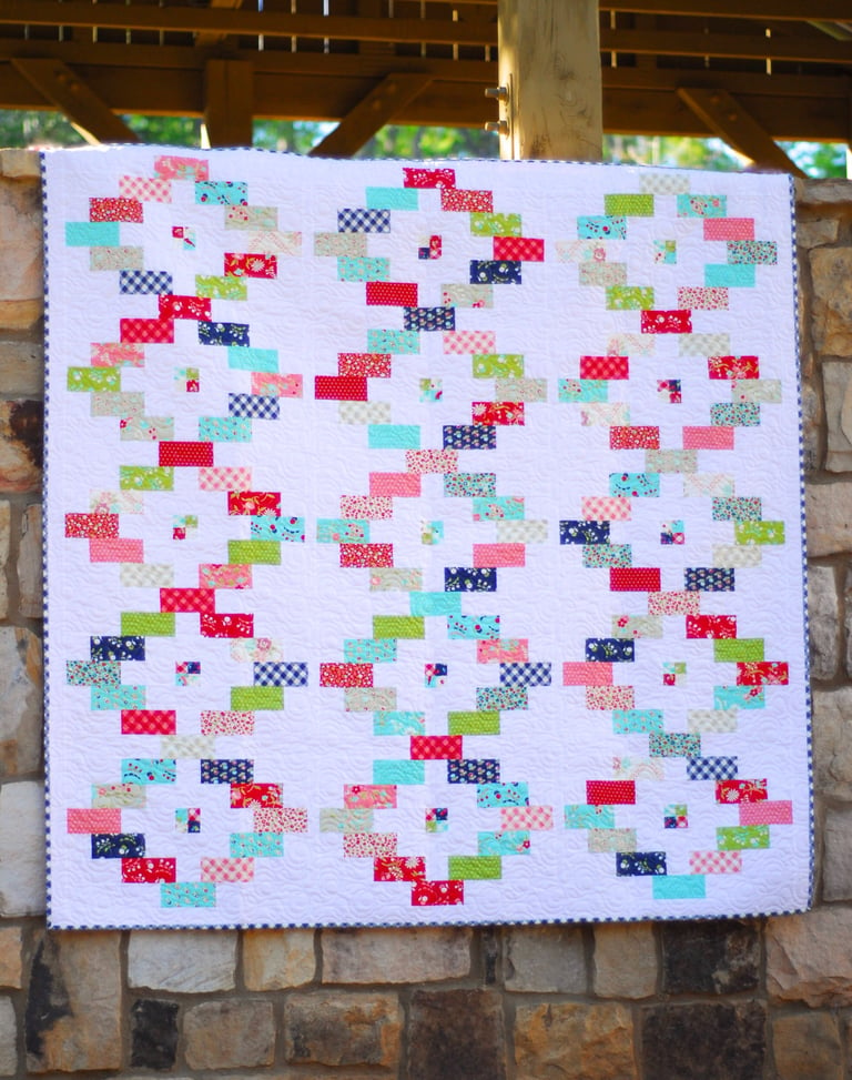 Colorful quilt with geometric pattern on a stone wall background