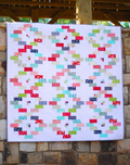 Colorful quilt with geometric pattern on a stone wall background