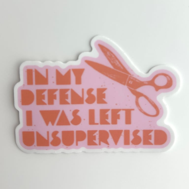 Sticker with scissors and text 'In my defense I was left unsupervised' on a light gray background