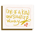Card with yellow text 'One of a Kind and Slightly Wonky' and a pair of scissors on a white background.