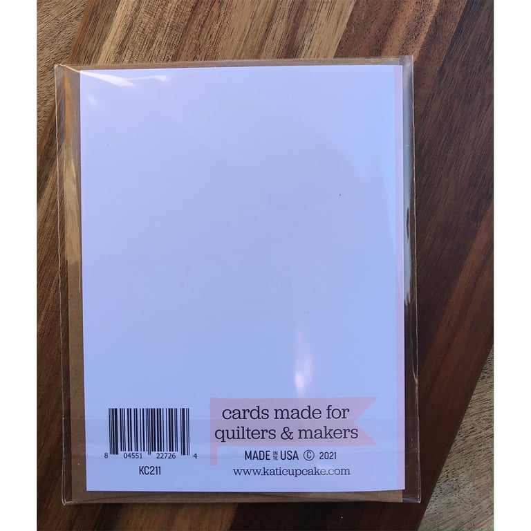 Packaged product with 'cards made for quilters & makers' text on a wooden surface