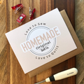 Box with 'Love to Sew Homemade Original Quilt Co' branding on a wooden surface with sewing tools.