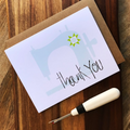 Greeting card with 'thank you' message and a small tool on a wooden surface