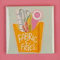 Button badge with fabric and scissors design on a pink background