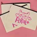Canvas pouches with a cat illustration and 'Feral' text on a pink background