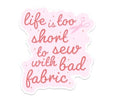 Motivational quote 'life is too short to sew with bad fabric' on a pink background