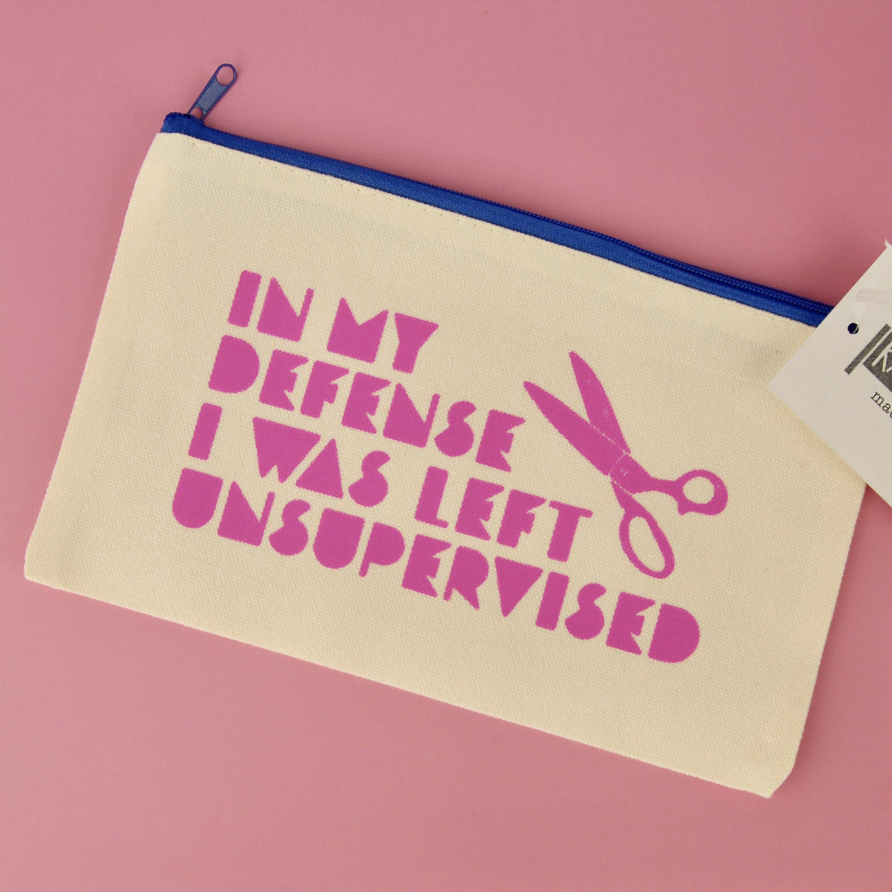 Beige pouch with pink text and scissors graphic on a pink background